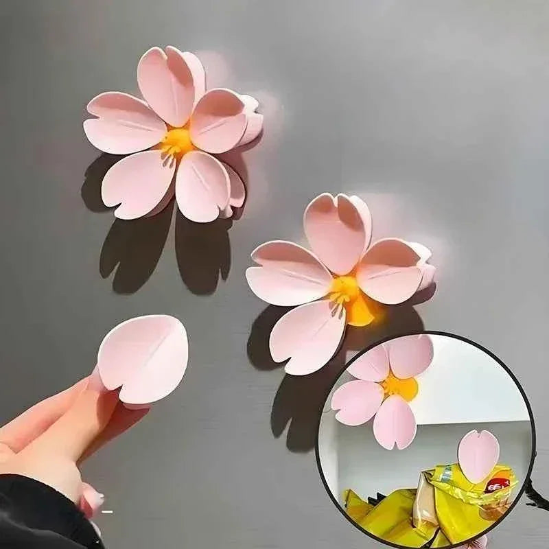 Pink cherry blossom fridge magnets with yellow centers, shown on metallic surface and holding items