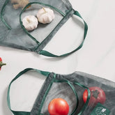 Reusable mesh grocery bags with fresh garlic and tomatoes for eco-friendly shopping