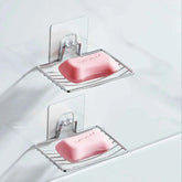 Stainless steel soap holders with pink bars, mounted on a tiled wall for bathroom organization.